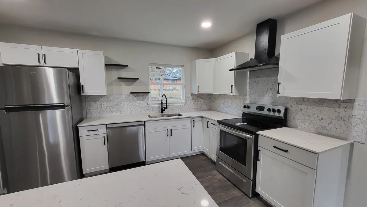 Finished kitchen with white cabinetry, black fixtures and a tiled backsplash
