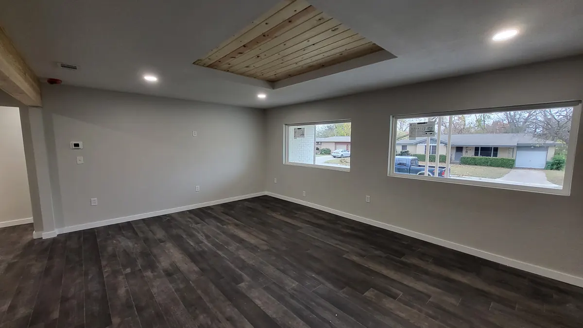 Finished living room with the same corner windows, new flooring and timber ceiling detail